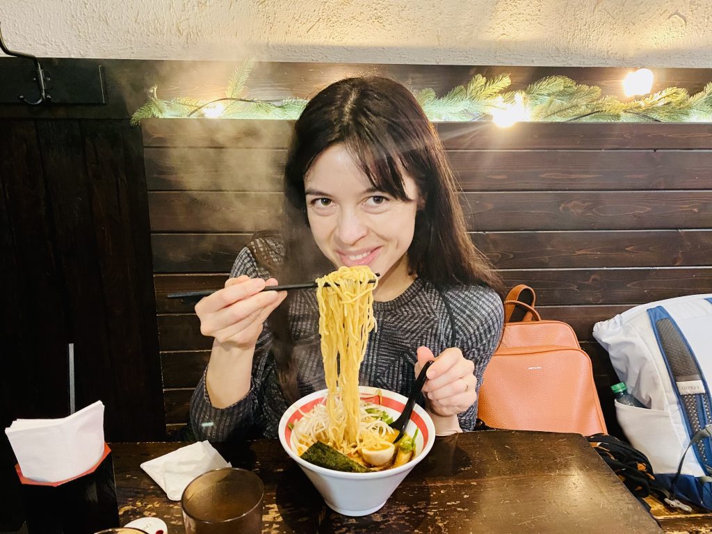 Agni enjoying a steaming bowl of ramen inside the cosy interior of Taishoken Ramen, one of Vancouver’s best ramen spots.